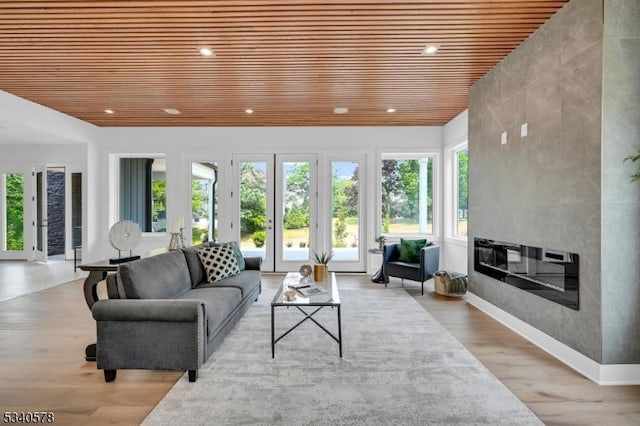 living area featuring a large fireplace, recessed lighting, wooden ceiling, and light wood-style floors