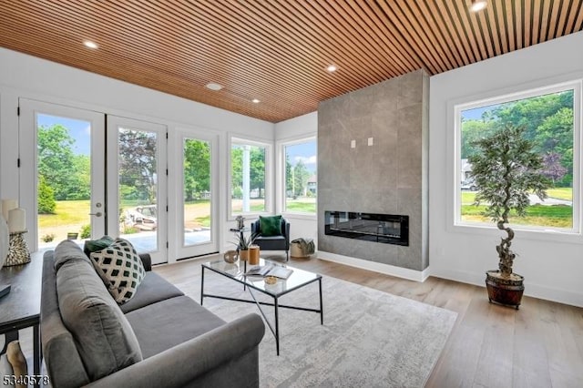 living room with wooden ceiling, a tile fireplace, recessed lighting, baseboards, and light wood finished floors