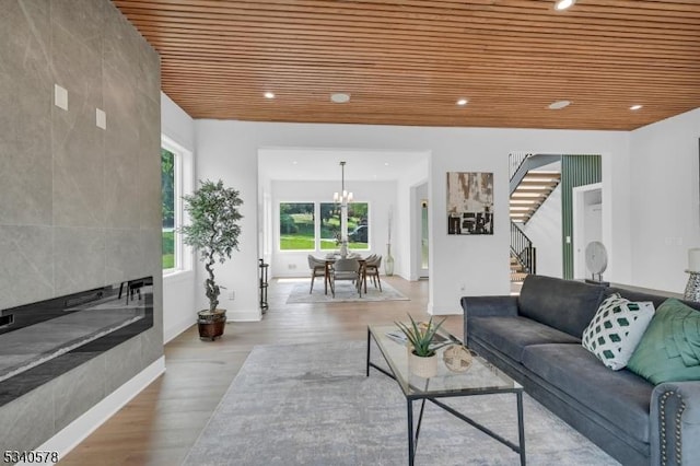 living area featuring stairs, wood ceiling, a fireplace, and wood finished floors