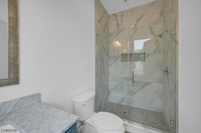 full bath with vanity, a marble finish shower, and toilet