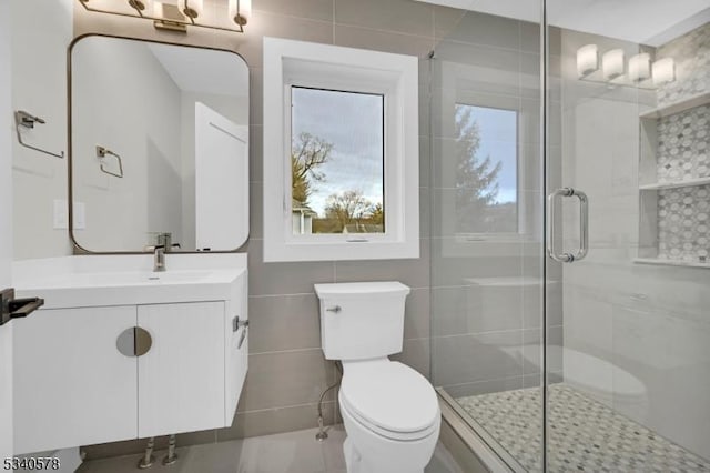 full bathroom with vanity, a shower stall, toilet, and tile walls