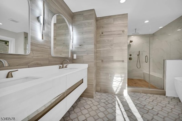 full bath featuring tile walls, recessed lighting, a sink, a shower stall, and a freestanding tub