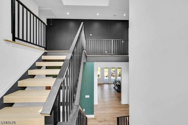 stairs featuring a high ceiling, baseboards, wood finished floors, and french doors