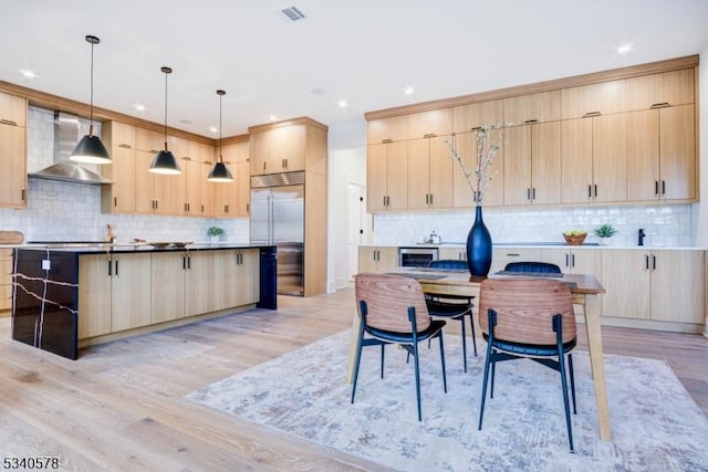 kitchen featuring stainless steel built in fridge, visible vents, wall chimney exhaust hood, and light brown cabinetry