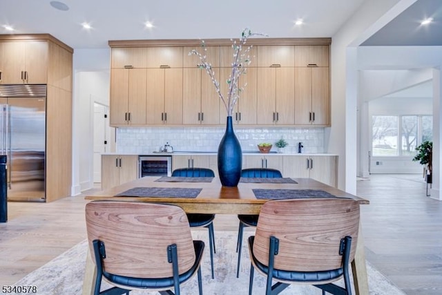 kitchen with decorative backsplash, wine cooler, light wood-type flooring, light brown cabinets, and built in fridge