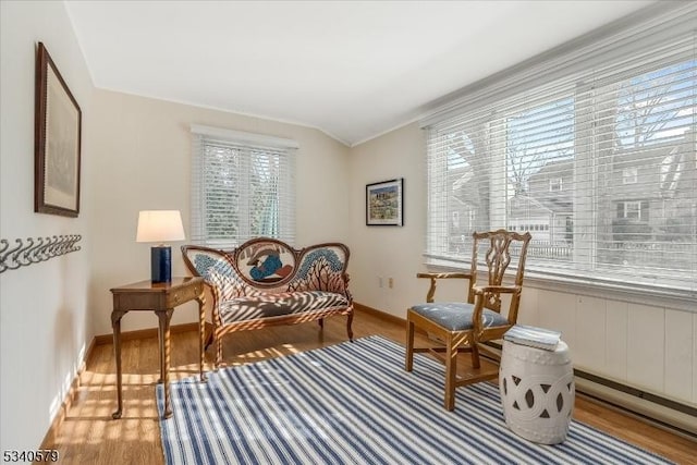 living area with vaulted ceiling, wood finished floors, and baseboards