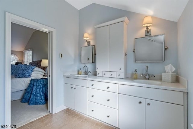 bathroom with lofted ceiling, a sink, ensuite bath, and double vanity