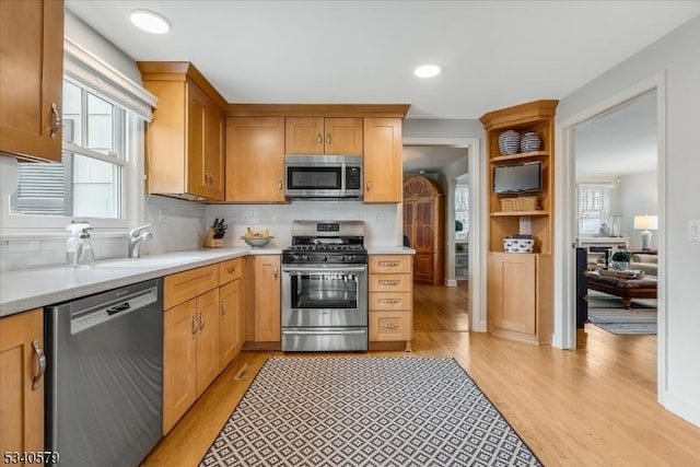 kitchen with appliances with stainless steel finishes, a wealth of natural light, light countertops, and light wood finished floors