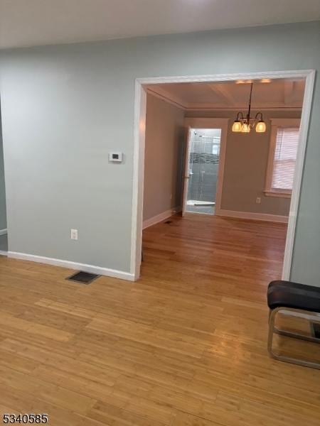 interior space with light wood finished floors, visible vents, a notable chandelier, and baseboards