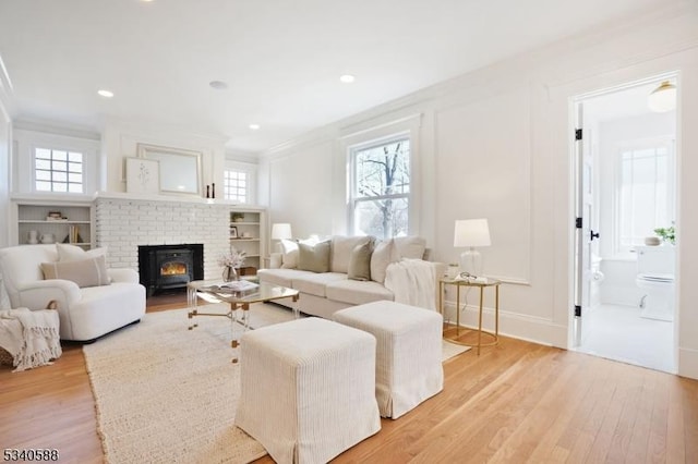 living area featuring light wood-style floors, a wealth of natural light, and crown molding