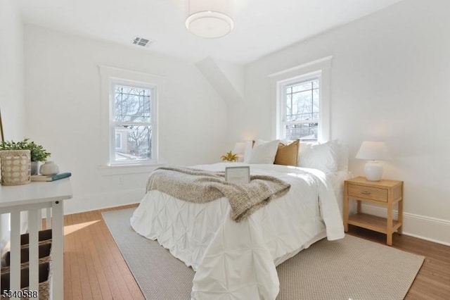 bedroom featuring visible vents, baseboards, and wood finished floors