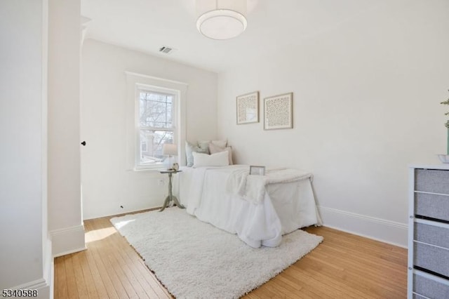 bedroom with hardwood / wood-style flooring, baseboards, and visible vents