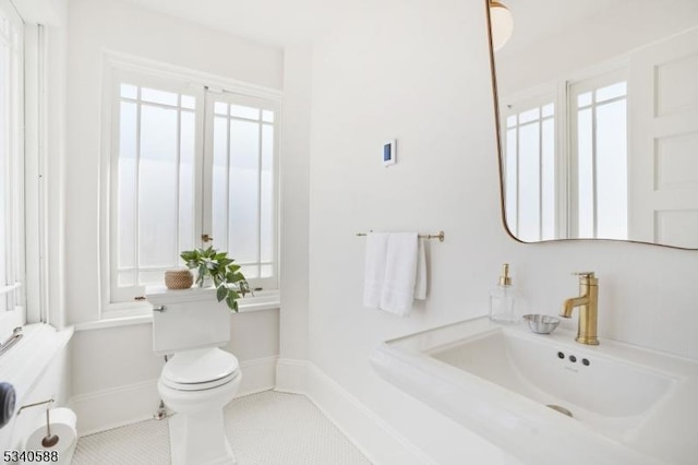 bathroom featuring baseboards, a sink, toilet, and tile patterned floors