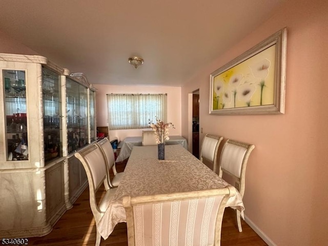 dining space with dark wood-type flooring and baseboards