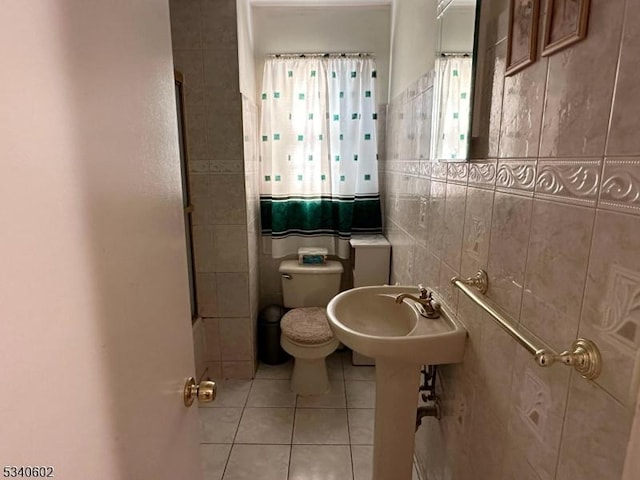 full bath featuring toilet, a sink, tile walls, and tile patterned floors