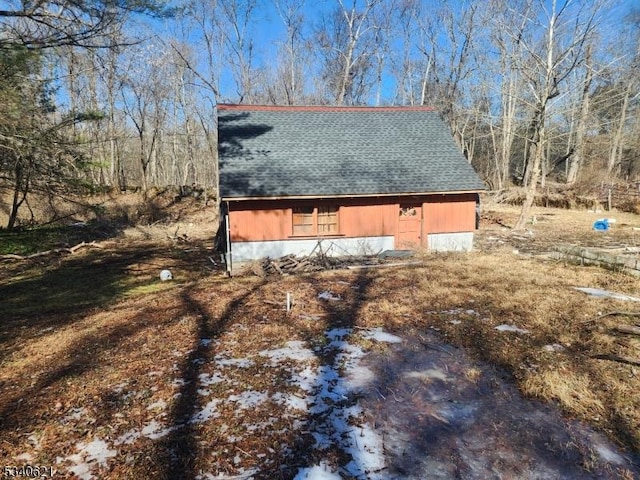 view of side of home with a barn, an outdoor structure, and roof with shingles