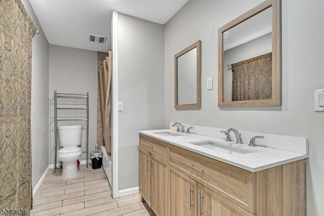 full bath with visible vents, a sink, toilet, and double vanity