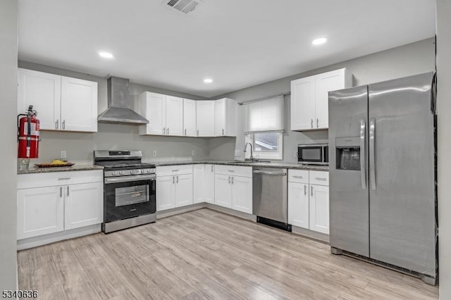 kitchen featuring stainless steel appliances, wall chimney exhaust hood, visible vents, and white cabinetry