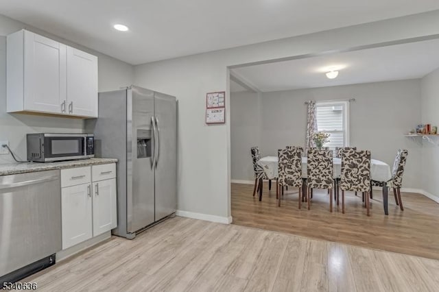 kitchen featuring light wood-style floors, white cabinetry, appliances with stainless steel finishes, and baseboards