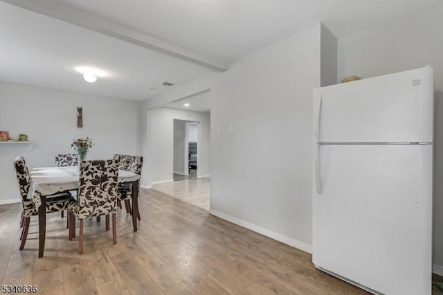 dining area with beamed ceiling, hardwood / wood-style flooring, and baseboards