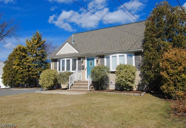 view of front facade with a front lawn and a shingled roof