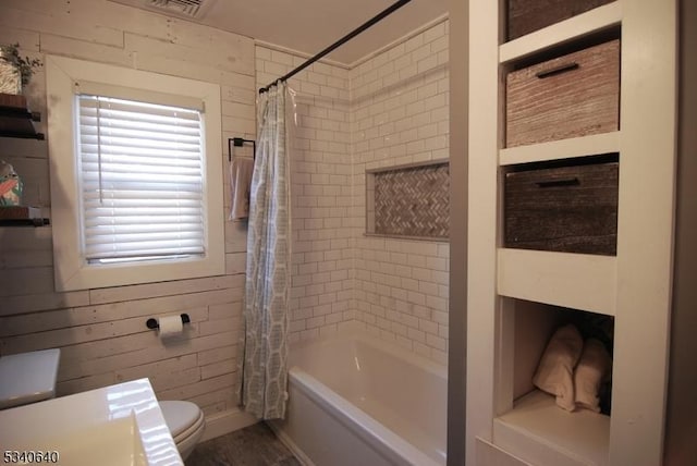 full bath with visible vents, wood walls, shower / bath combo with shower curtain, and toilet