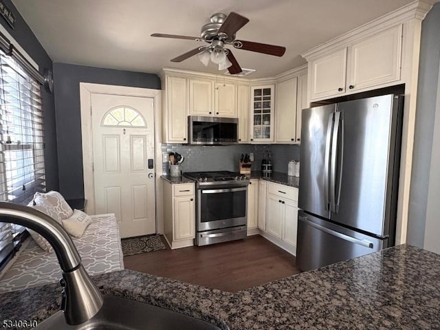 kitchen featuring tasteful backsplash, dark wood-style floors, glass insert cabinets, appliances with stainless steel finishes, and a sink