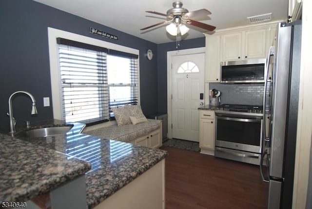 kitchen with visible vents, decorative backsplash, dark wood-style floors, appliances with stainless steel finishes, and a sink