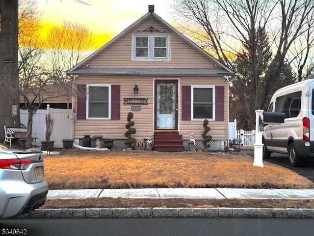 bungalow-style home featuring entry steps and fence