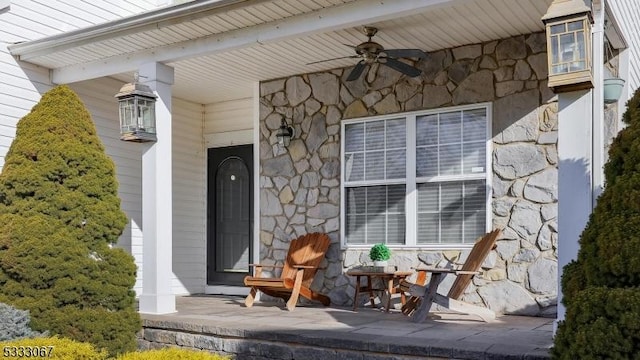 property entrance with covered porch, stone siding, and a ceiling fan