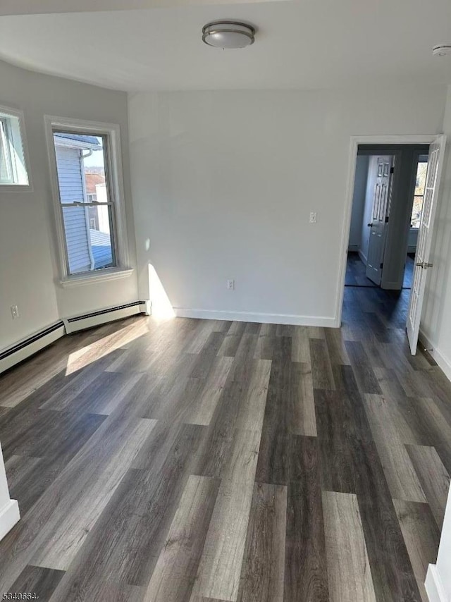 empty room with a baseboard heating unit, wood finished floors, and baseboards