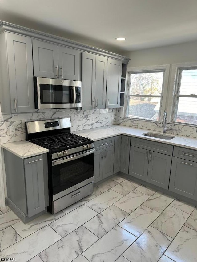 kitchen featuring marble finish floor, stainless steel appliances, a sink, and gray cabinetry