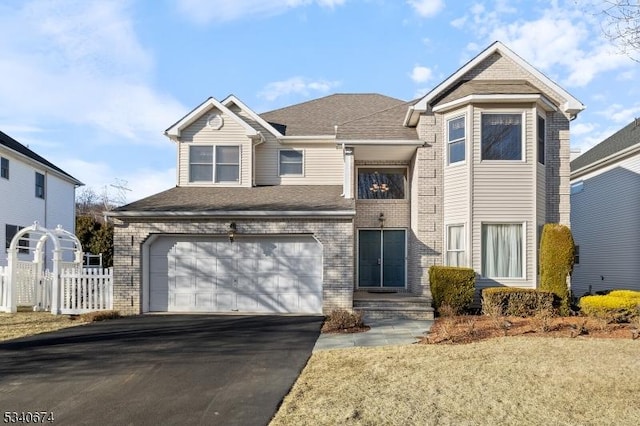 traditional-style home with a garage, fence, aphalt driveway, and brick siding