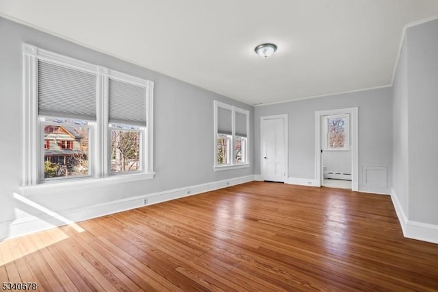 unfurnished room with baseboards, a baseboard heating unit, and wood finished floors