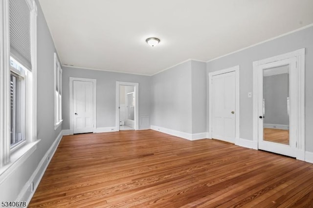 empty room featuring crown molding, baseboards, and wood finished floors