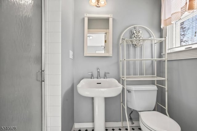 full bathroom featuring toilet, baseboards, a sink, and a shower with shower door