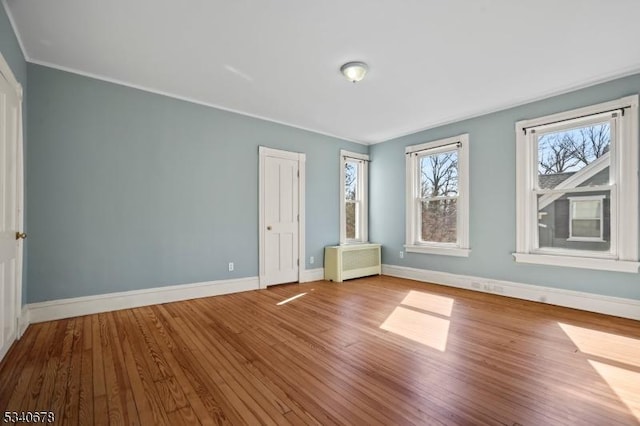 unfurnished bedroom featuring radiator, baseboards, and wood finished floors