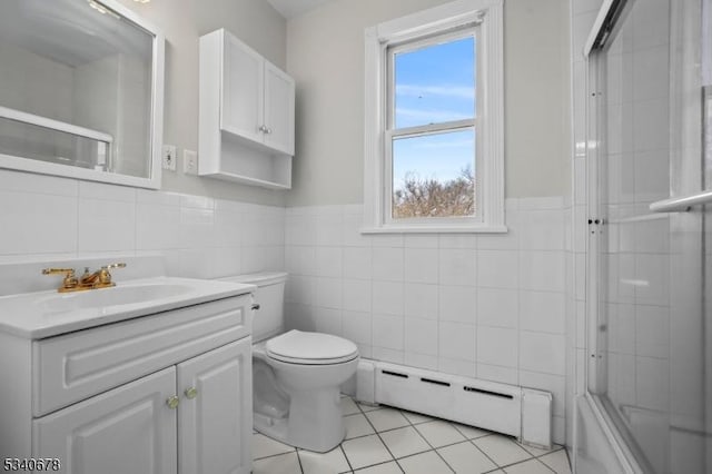 full bathroom featuring toilet, tile patterned flooring, vanity, a baseboard heating unit, and tile walls