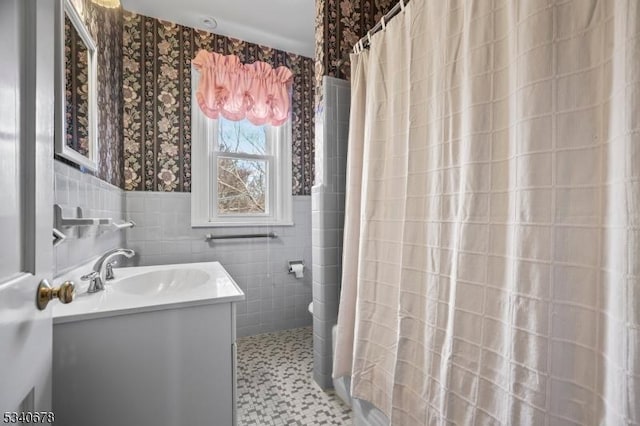 bathroom featuring tile walls, curtained shower, toilet, vanity, and wallpapered walls