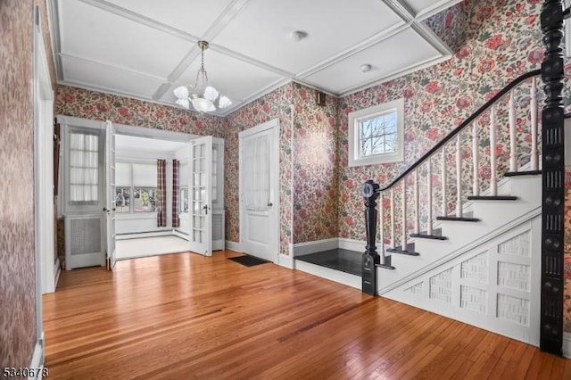 foyer entrance with wallpapered walls, stairway, coffered ceiling, and wood finished floors