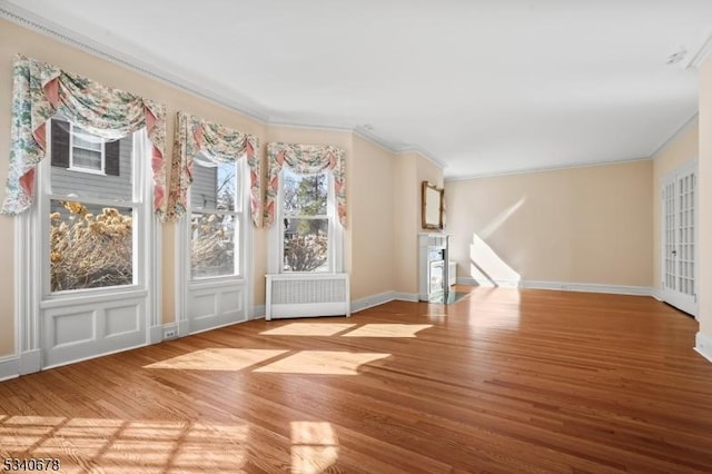 interior space with radiator, crown molding, baseboards, and wood finished floors