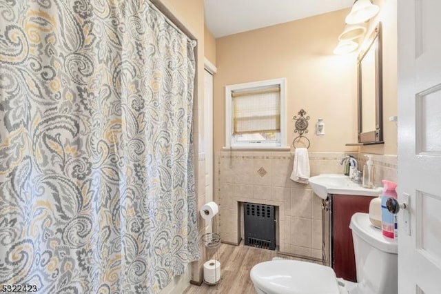 full bath featuring toilet, a wainscoted wall, vanity, tile walls, and radiator heating unit