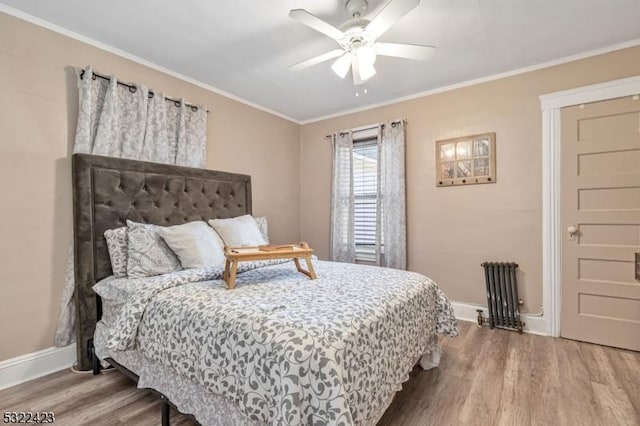 bedroom with baseboards, radiator heating unit, ceiling fan, wood finished floors, and crown molding