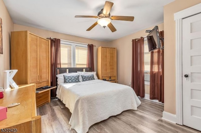 bedroom with wood finished floors, a ceiling fan, and baseboards