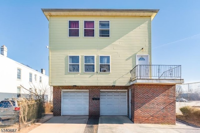 view of front of property with a garage, fence, concrete driveway, and brick siding