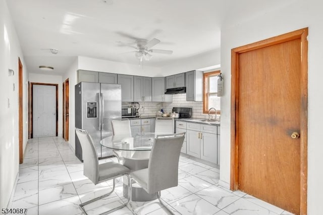 kitchen featuring tasteful backsplash, appliances with stainless steel finishes, marble finish floor, gray cabinets, and a sink