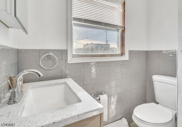 half bath featuring toilet, vanity, and tile walls