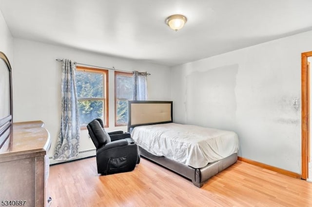 bedroom featuring a baseboard radiator, baseboards, and wood finished floors