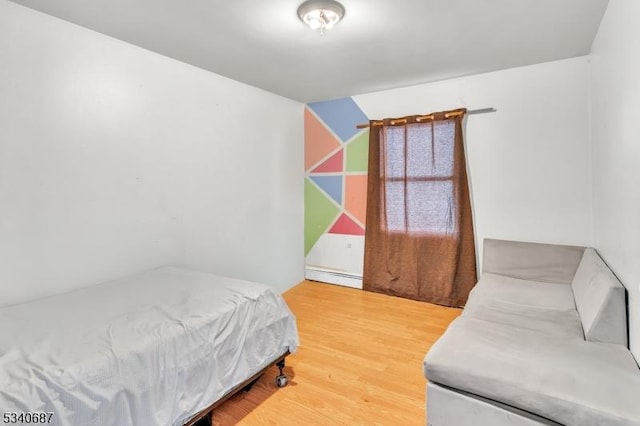 bedroom featuring a baseboard heating unit and wood finished floors