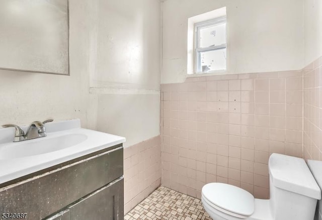 bathroom featuring tile walls, toilet, and vanity